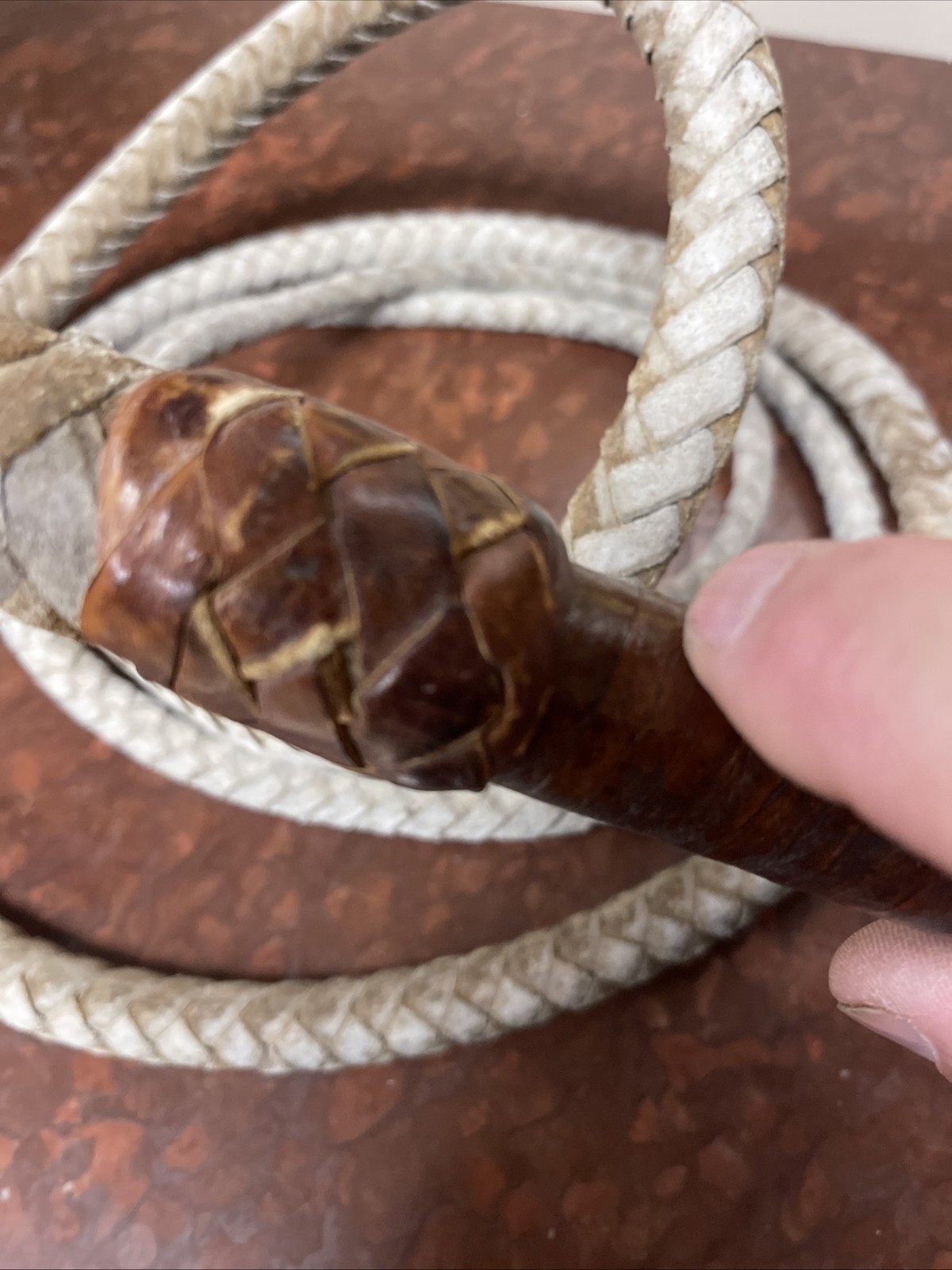 Vintage braided leather bullwhip with a patterned handle.