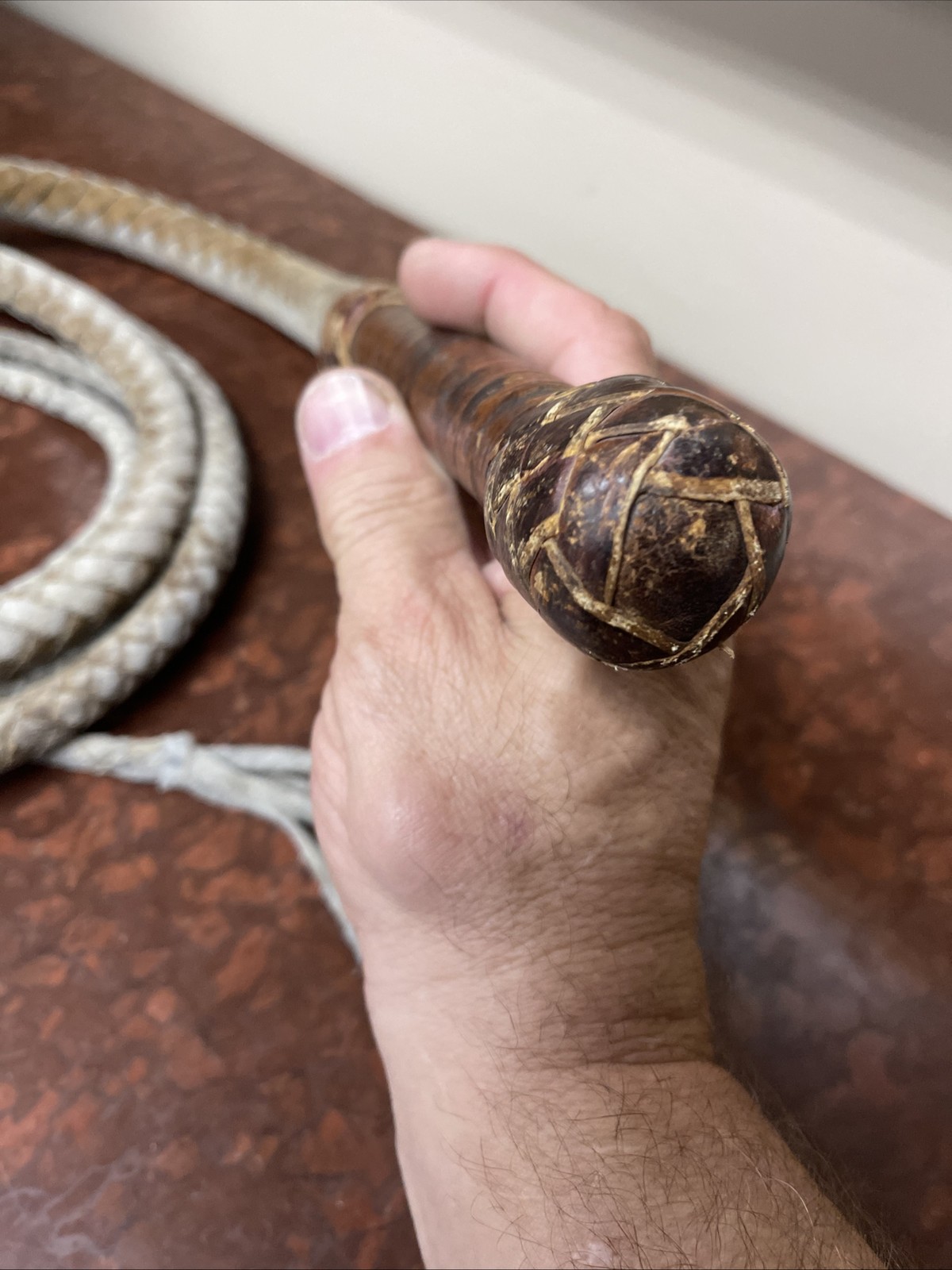 Vintage braided leather bullwhip with a patterned handle.