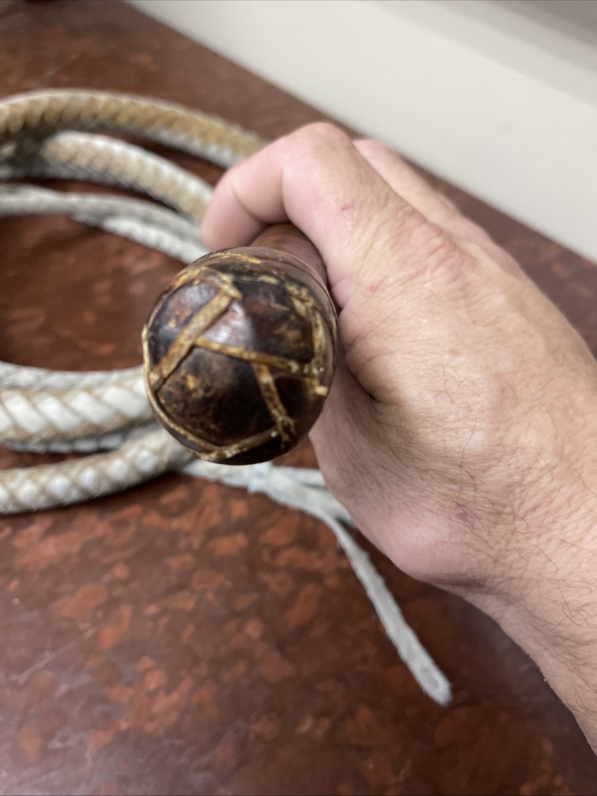 Vintage braided leather bullwhip with a patterned handle.