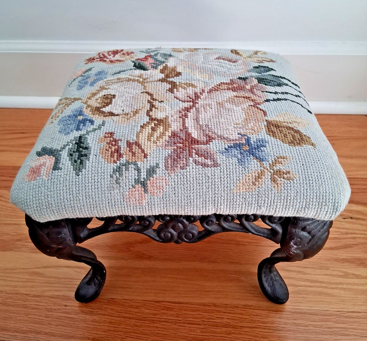 Vintage needlepoint ottoman stool with floral design and cast iron legs