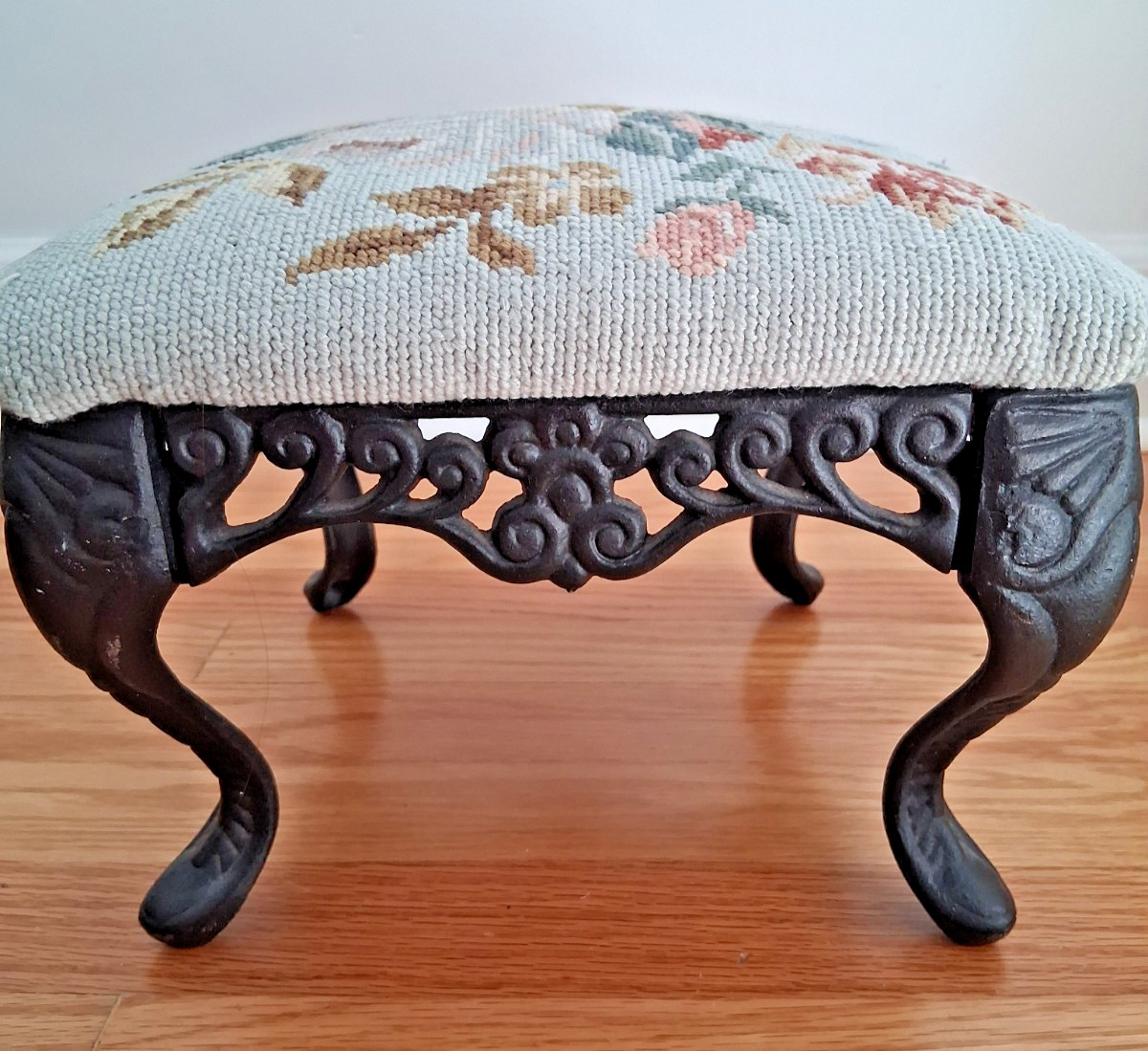 Vintage needlepoint ottoman stool with floral design and cast iron legs