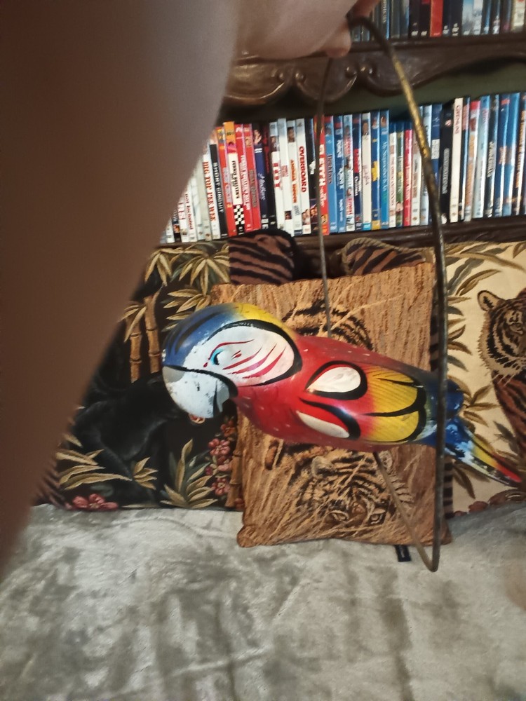 Worn painted ceramic parrot on metal perch,ceiling hanger.