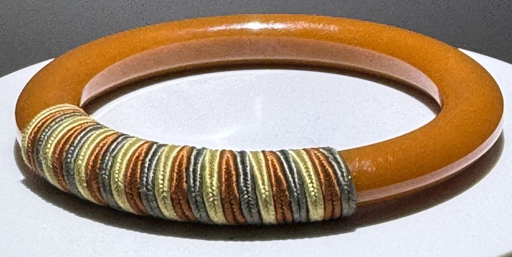 Red/white/blue string-wrapped, rust-colored Bakelite bracelet; tested
