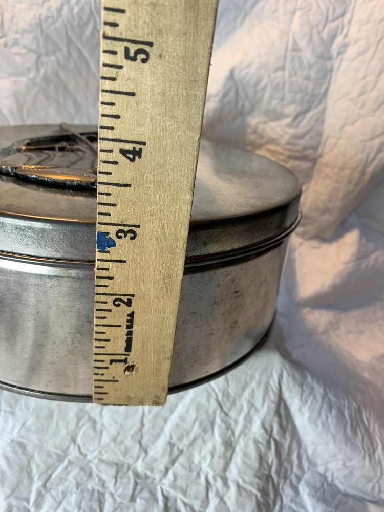 round silver tin with metal golf plaque affixed