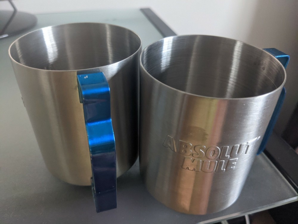 Two stainless absolute mule vodka glasses with blue metal handle