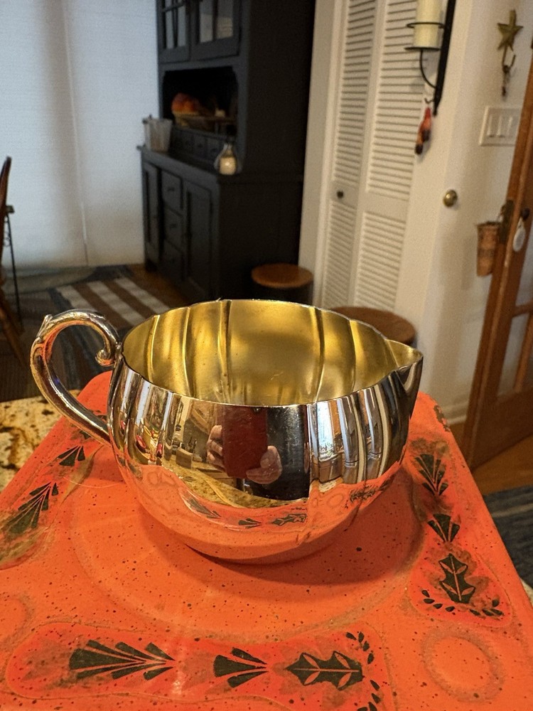 A vintage Oneida silver-plated fluted creamer with a decorative handle.