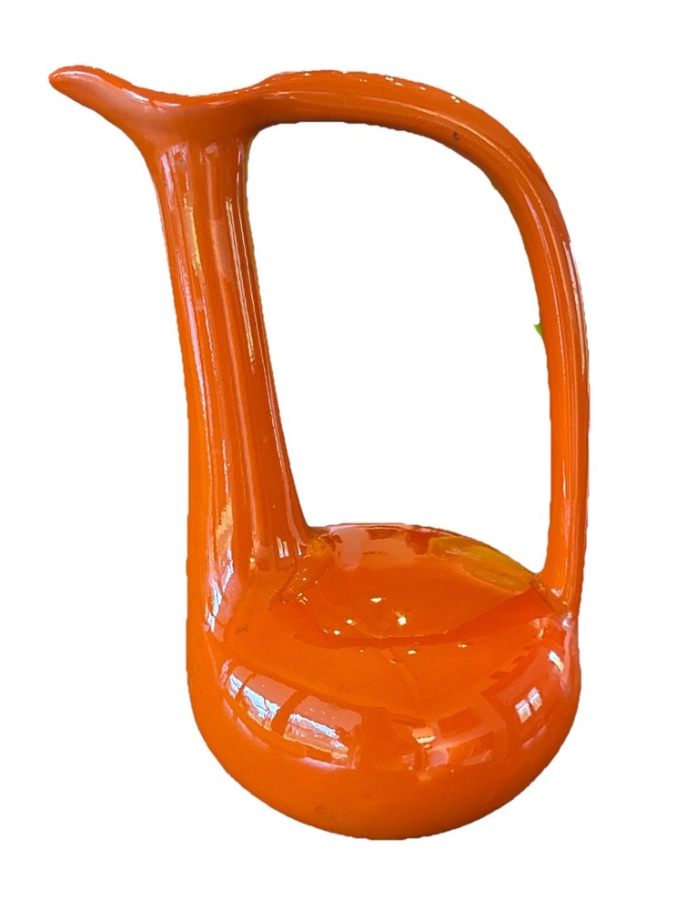 A vibrant orange, mid-century modern sculptural ceramic pitcher.