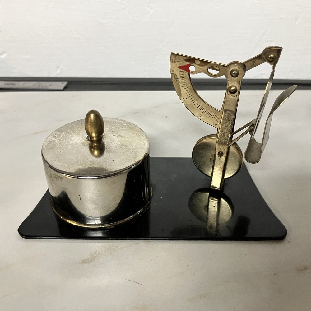 Possibly a brass postage stamp roll holder/dispenser and letter scale