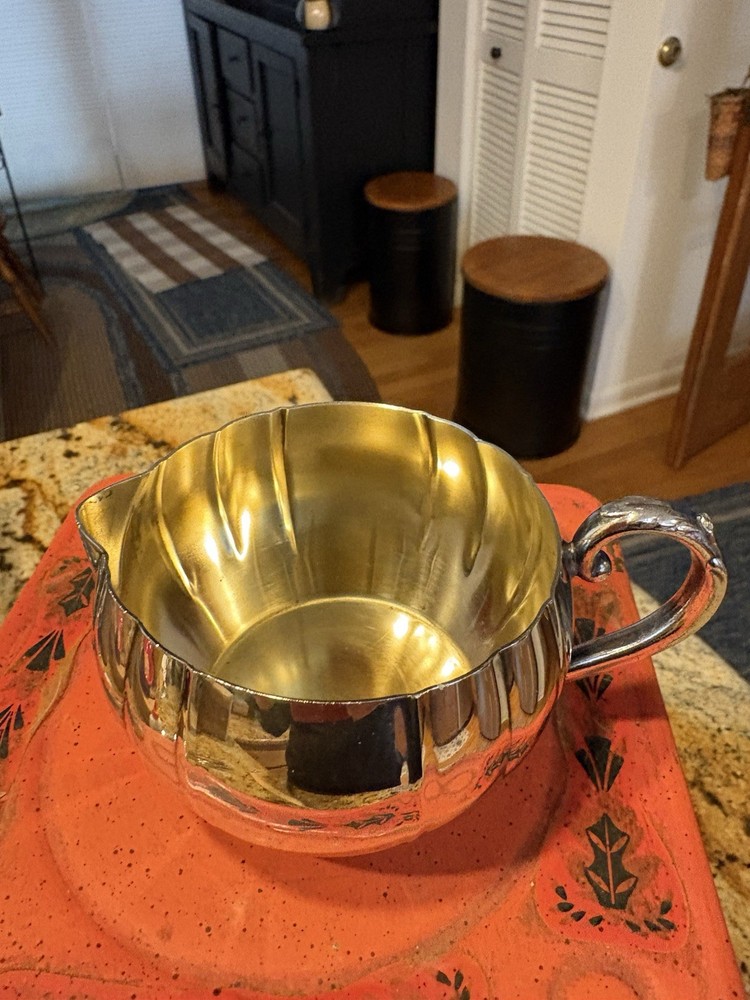 A vintage Oneida silver-plated fluted creamer with a decorative handle.