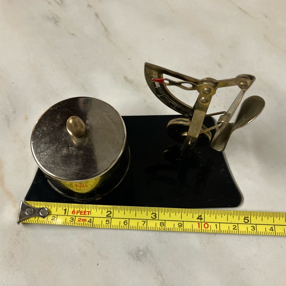 Possibly a brass postage stamp roll holder/dispenser and letter scale