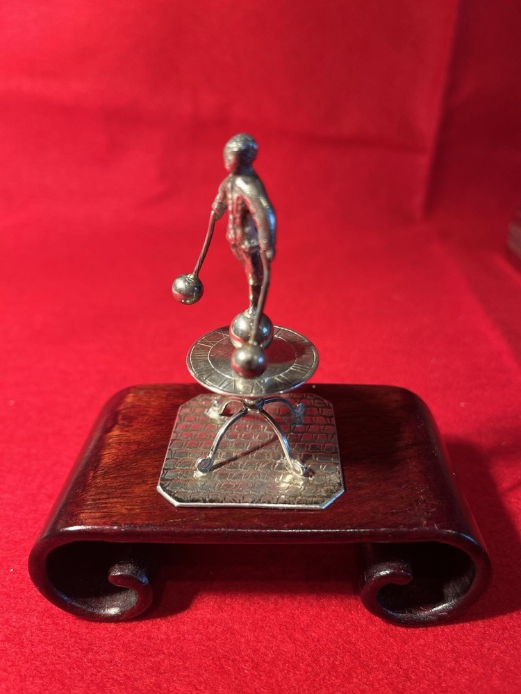 silver miniature man standing on sun dial man roates