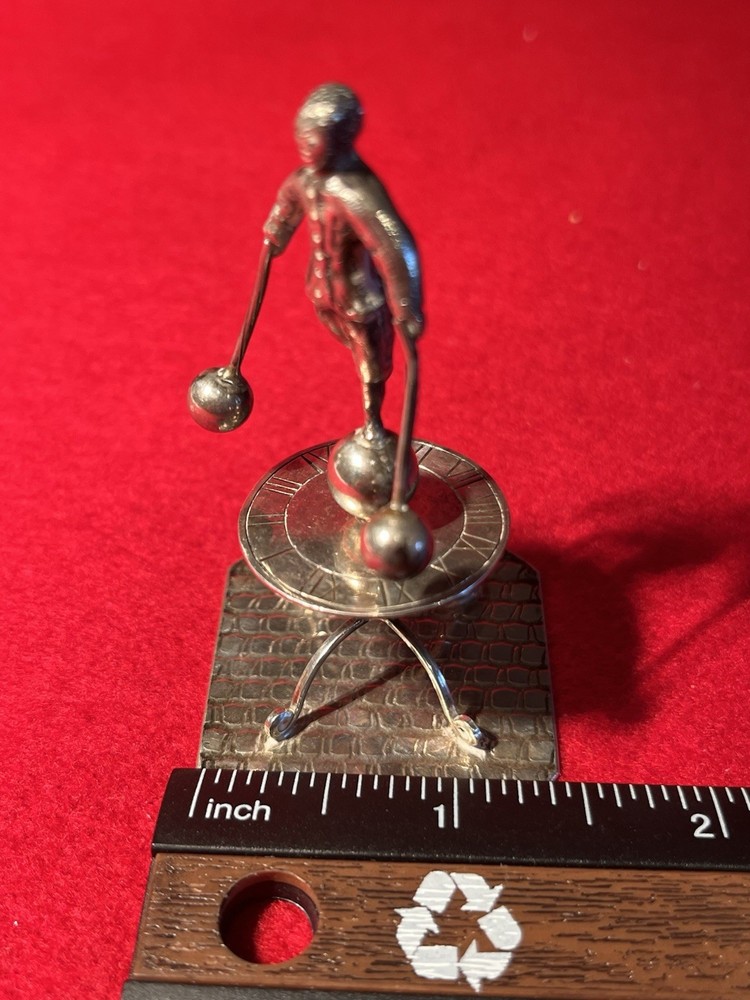 silver miniature man standing on sun dial man roates