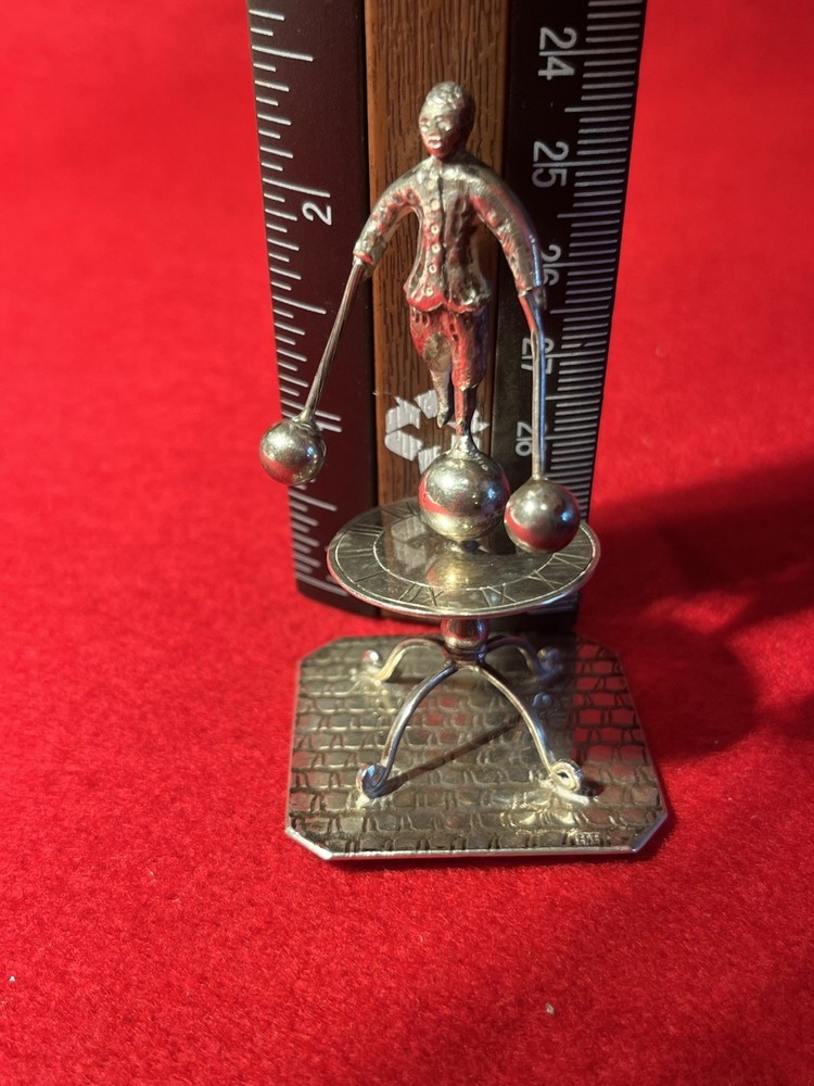 silver miniature man standing on sun dial man roates