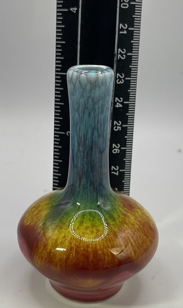 a small, multicolored, drip-glazed ceramic vase.