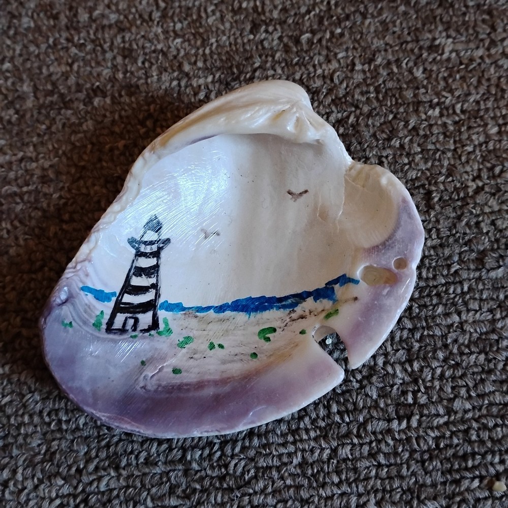 hand-painted seashell featuring a lighthouse scene