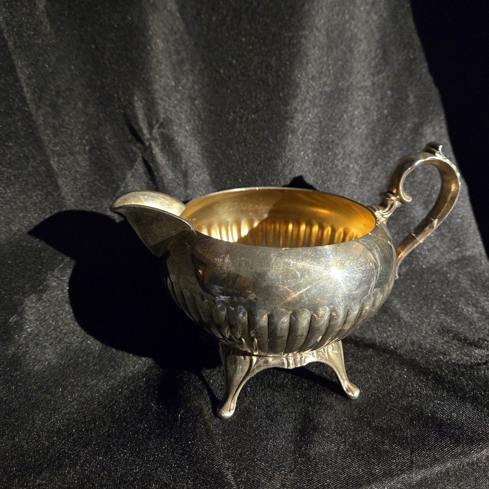 A silver-plated Wm. A. Rogers footed creamer pitcher with fluted body.