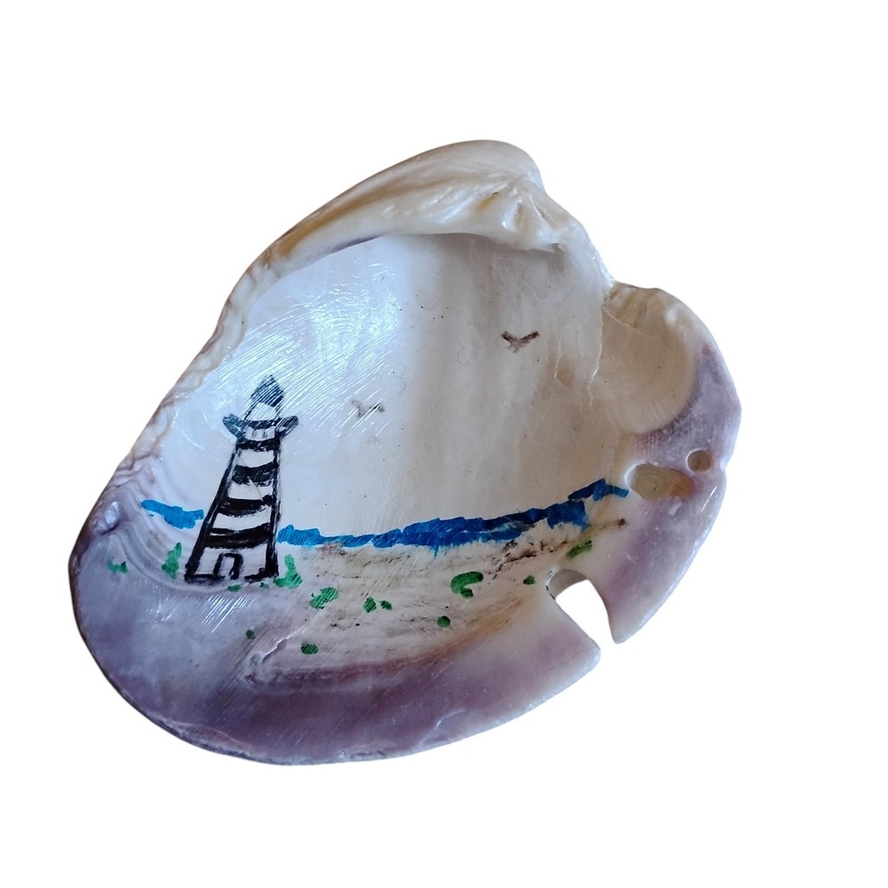 hand-painted seashell featuring a lighthouse scene