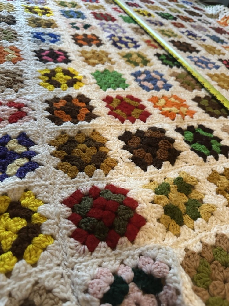 Handmade crocheted granny square blanket with a green border.