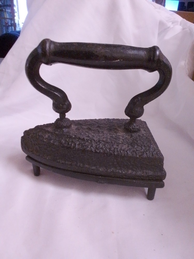 Antique cast iron sad iron with a dark handle and textured surface.
